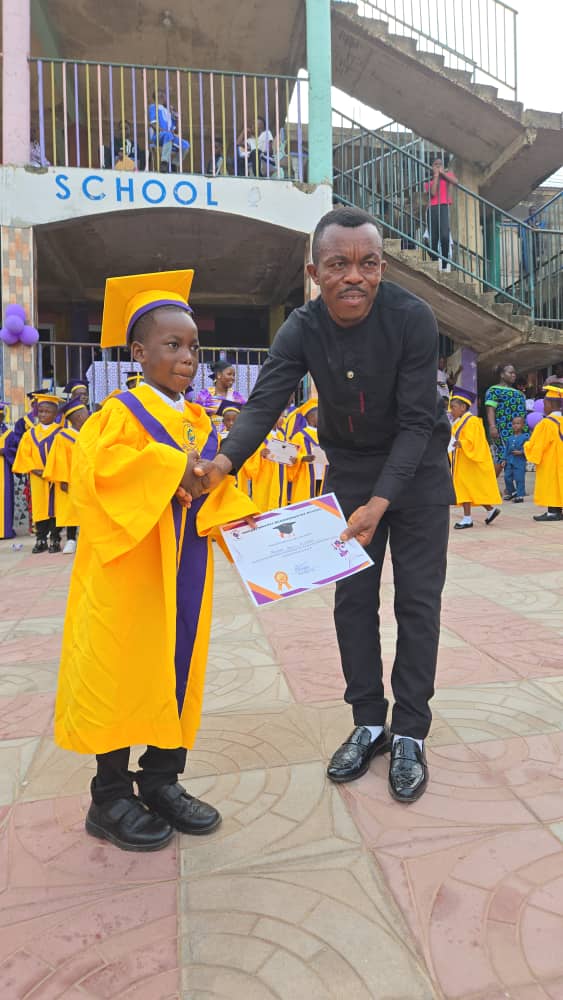A young graduate in a gold gown receiving a certificate